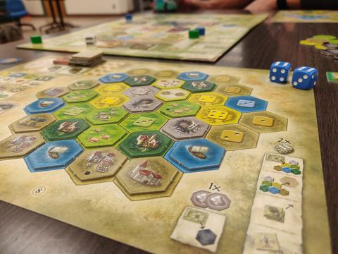 Castles of Burgundy board game, focused on personal player's mat with two blue dice in top right corner, showing tiles placed in the foreground and the general mat in the background.