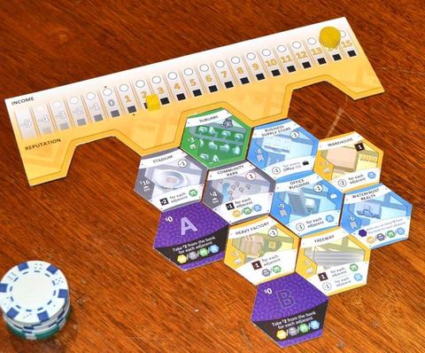 Borough board (with income and reputation tracks) and borough development (hex tiles) in board game Suburbia.